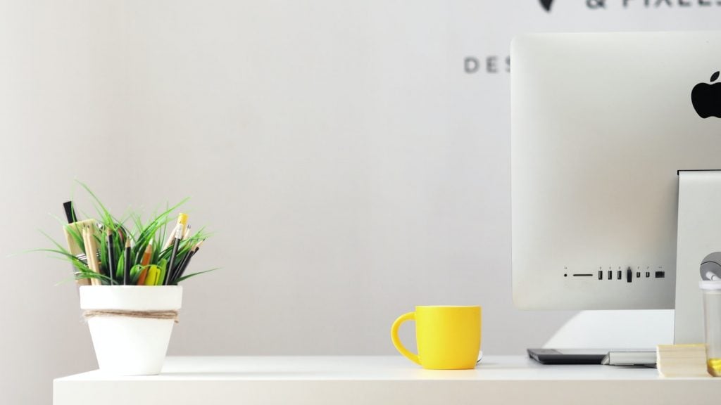 working form home set up - office deks with computer, plant and mug