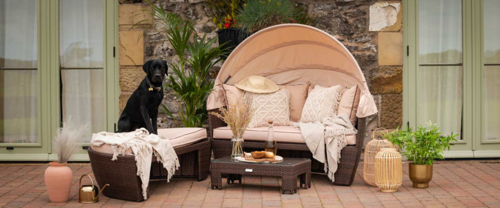 A picture of a rattan day bed with a dog on the bench