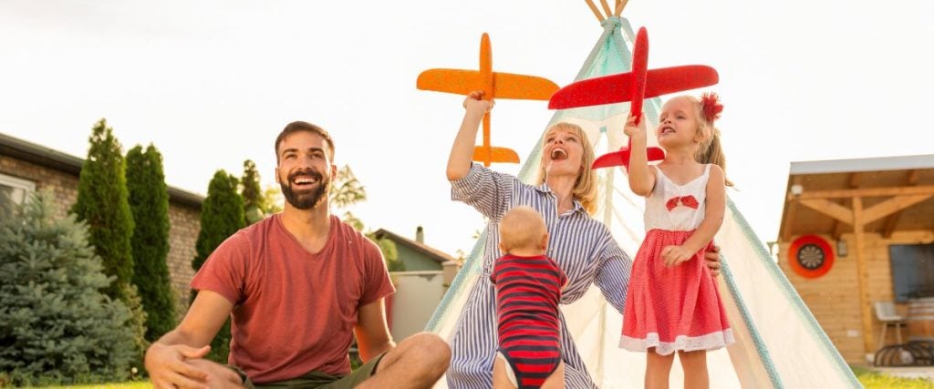 A picture of a family camping and flying paper planes in the garden 