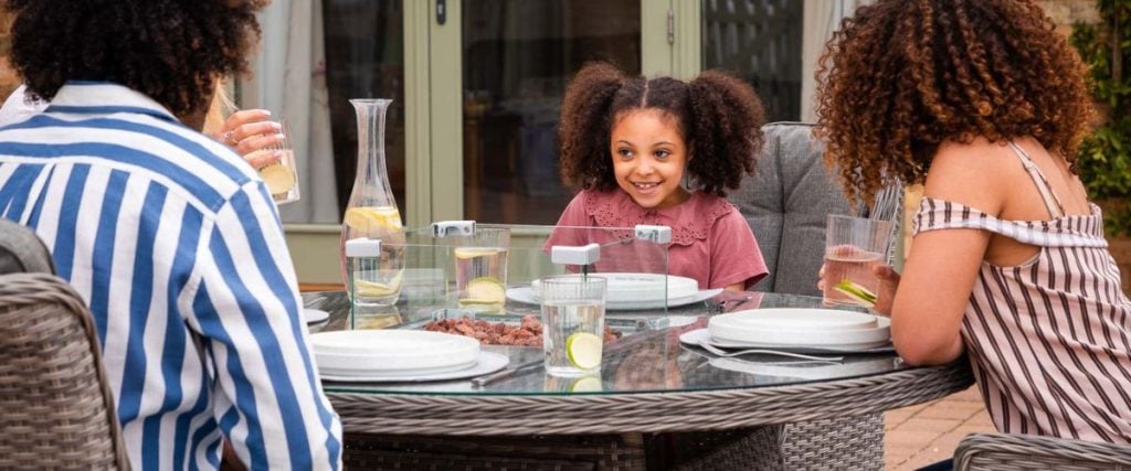 A picture of a smiling little girl seated at a dining table: round dining table