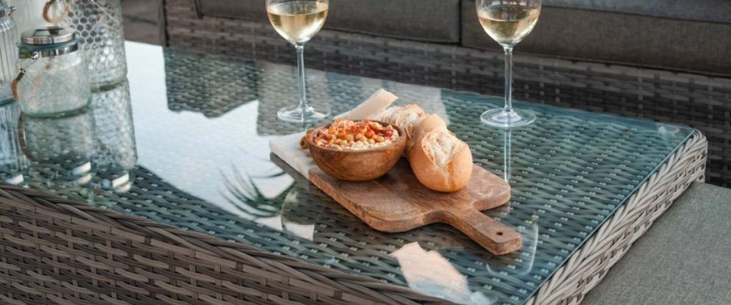 A picture of some food and wine glasses on a rattan coffee table: outdoor furniture features